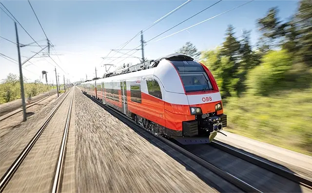 Moderne ÖBB-Schnellzug-Garnitur in voller Fahrt auf einer elektrifizierten Bahnstrecke. Repräsentiert nachhaltige Mobilität und Pünktlichkeit im österreichischen Schienenverkehr.