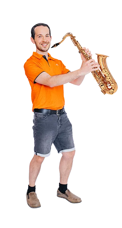 Andreas Kritsch, MSc steht mit einem Saxophon in den Händen und lächelt in die Kamera – musikalisch, humorvoll und voller Spielfreude.
