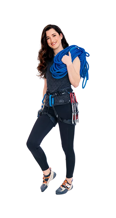 Lisa Videnova, MA MSc trägt Kletterausrüstung mit Seil über der Schulter und Karabinern am Gurt - mutig, sportlich und bereit für das nächste Abenteuer in der Vertikalen.