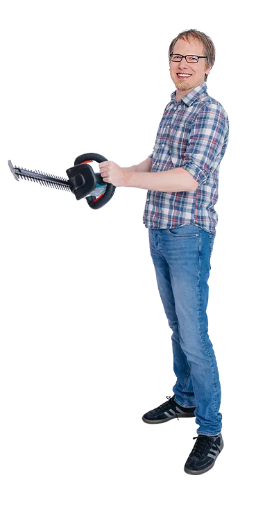 Mag. Martin Fuchs steht mit einer Heckenschere in den Händen und lächelt in die Kamera – engagiert, bodenständig und mit Sinn für praktische Aufgaben.