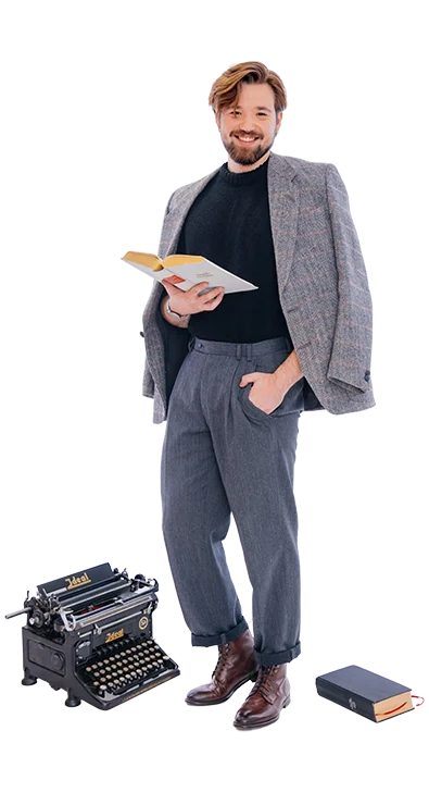 Philipp Zelenka, BSc MSc steht elegant mit Buch in der Hand, neben sich eine alte Schreibmaschine und ein weiteres Buch - stilvoll, belesen und mit einem Hauch Retro-Charme.