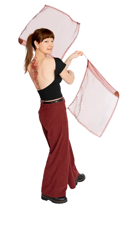 Luca Zsofia Trapp, MSc dreht sich in Bewegung mit zwei leichten Tüchern in den Händen, ein auffälliges Tattoo auf dem Rücken sichtbar.